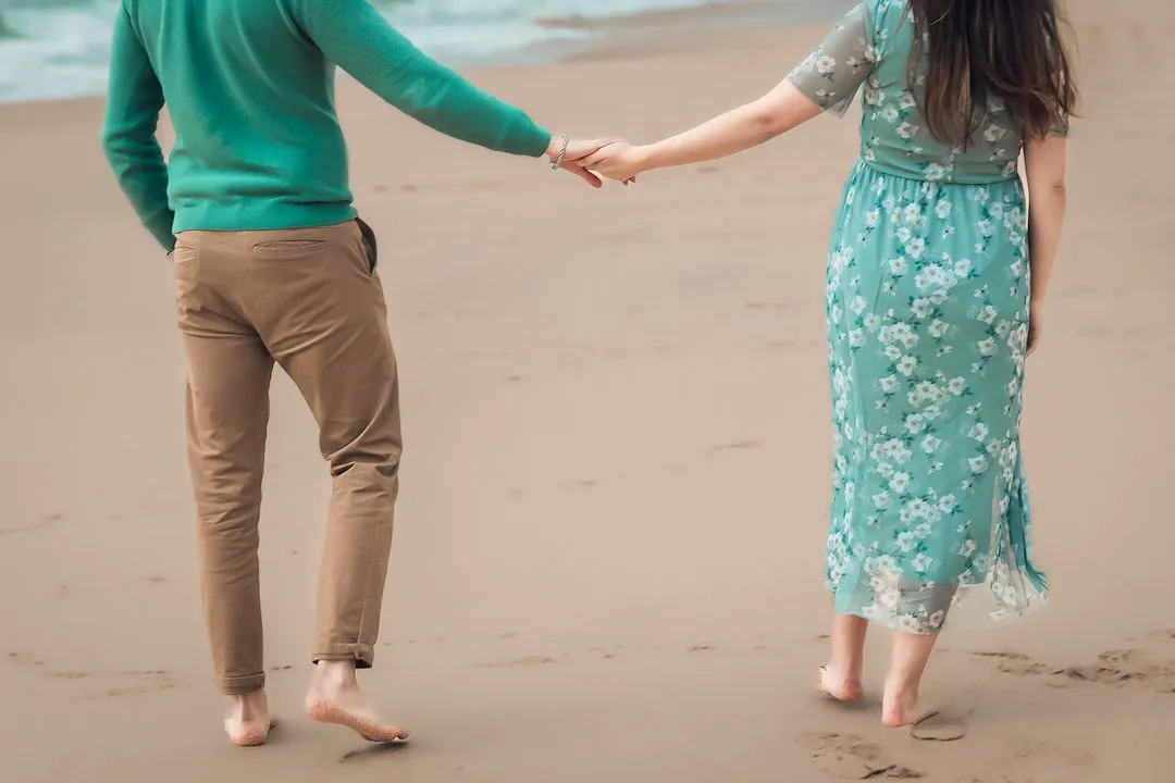 Mãos dadas a caminhar na areia